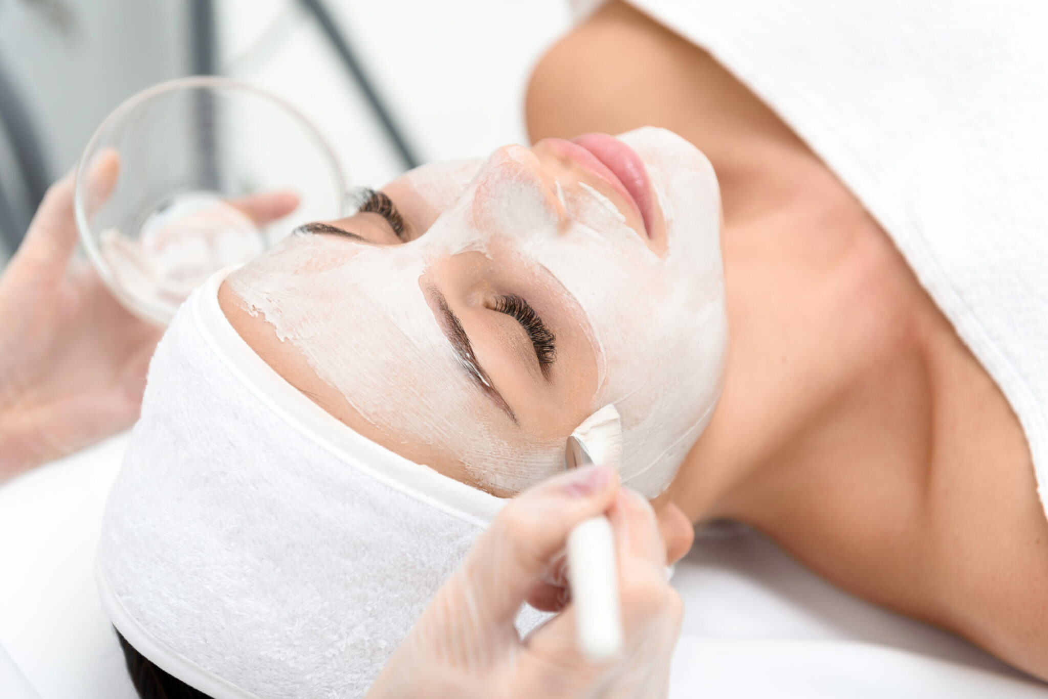 Close up of female face getting healthy clay mask by beautician