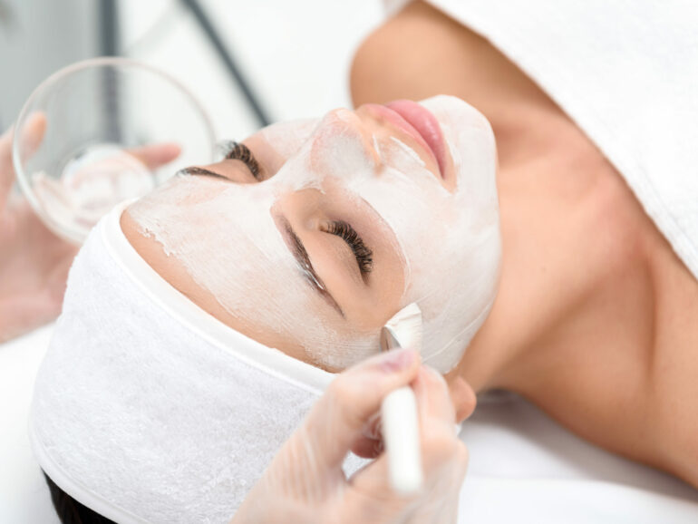 Close up of female face getting healthy clay mask by beautician