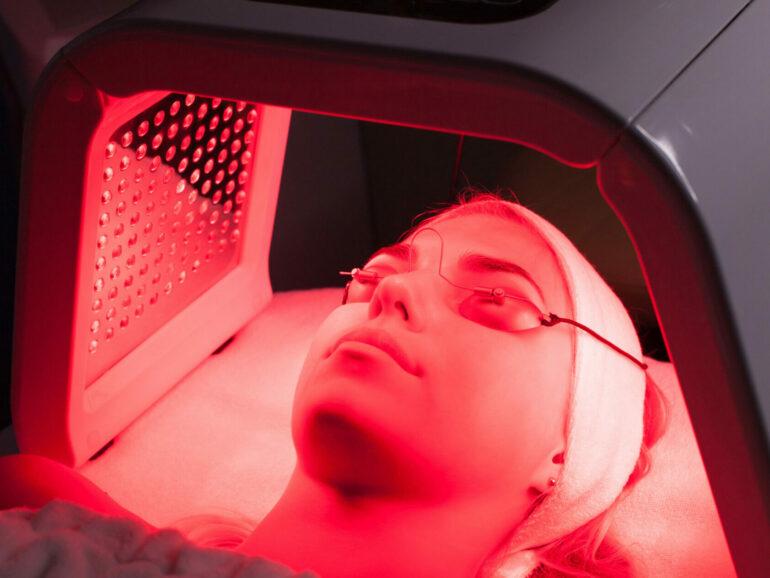 Young woman having LED light facial treatment in beauty salon