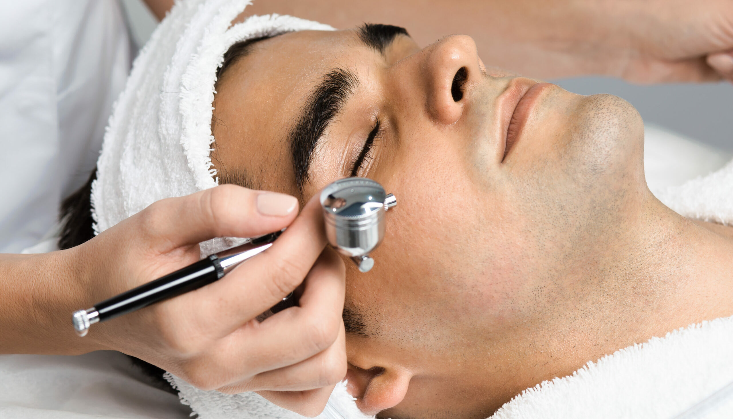 Facial beauty treatment of good looking man with oxygen epidermal peeling at cosmetic beauty salon.