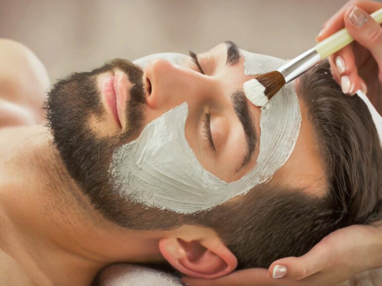 Man receiving a Facial Clay Mask in Wellness Resort or Spa - Relaxation and Skin Care done by Beautician